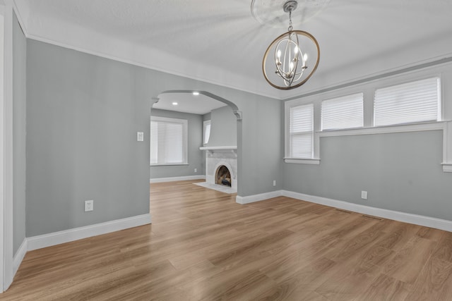 unfurnished living room with an inviting chandelier and light wood-type flooring