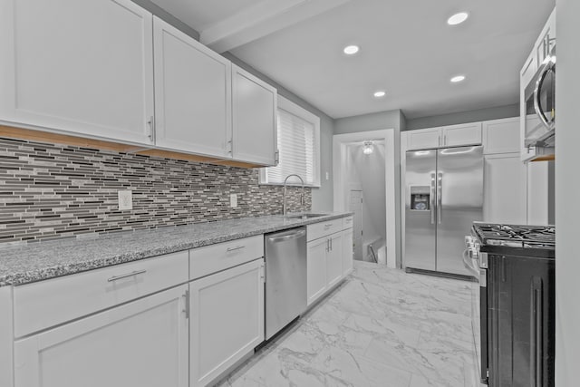 kitchen with white cabinetry, appliances with stainless steel finishes, sink, and light stone counters