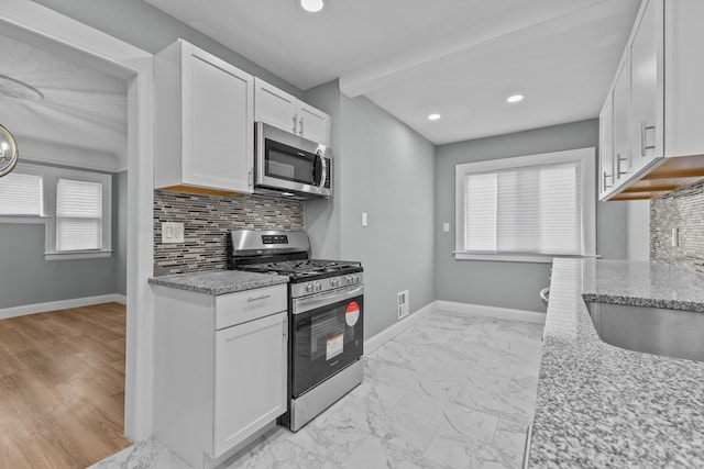 kitchen with white cabinetry, appliances with stainless steel finishes, and light stone counters