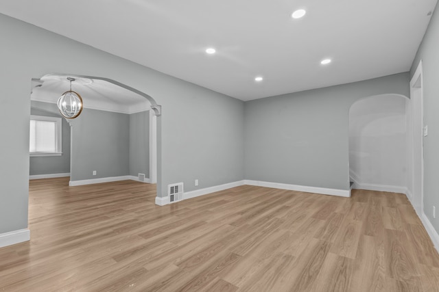 empty room with a chandelier and light wood-type flooring