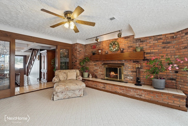 tiled living room with ceiling fan, a fireplace, and a textured ceiling