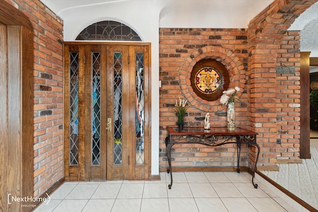 tiled foyer entrance featuring brick wall