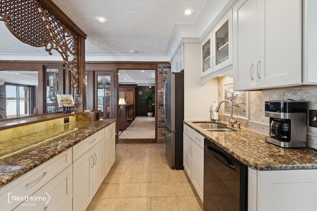 kitchen featuring sink, stainless steel refrigerator, dishwasher, white cabinets, and dark stone counters