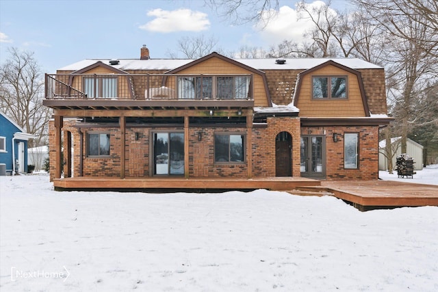 snow covered house featuring a balcony