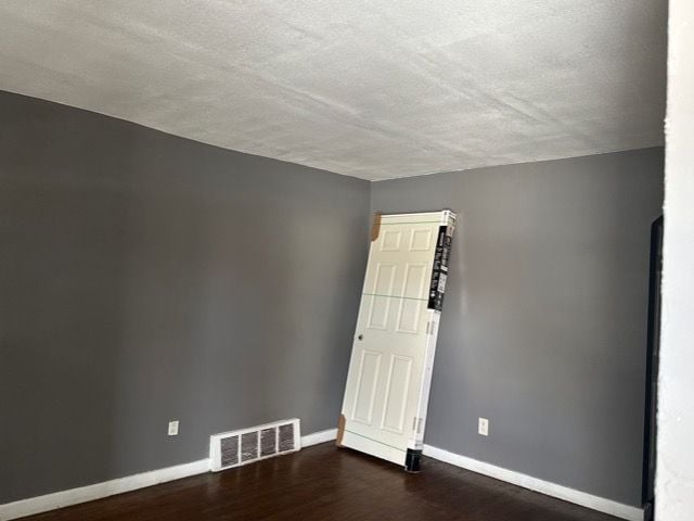 empty room with dark hardwood / wood-style floors and a textured ceiling