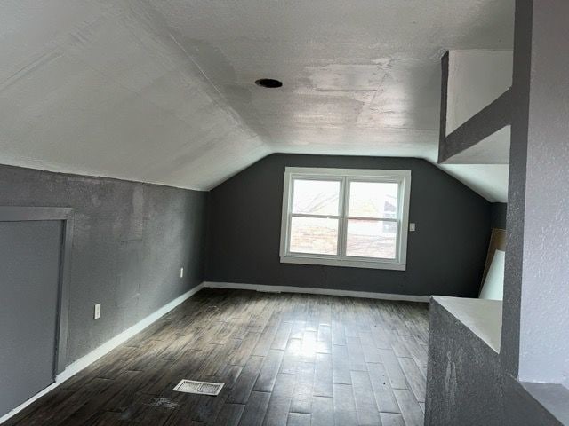 bonus room featuring dark wood-type flooring and lofted ceiling