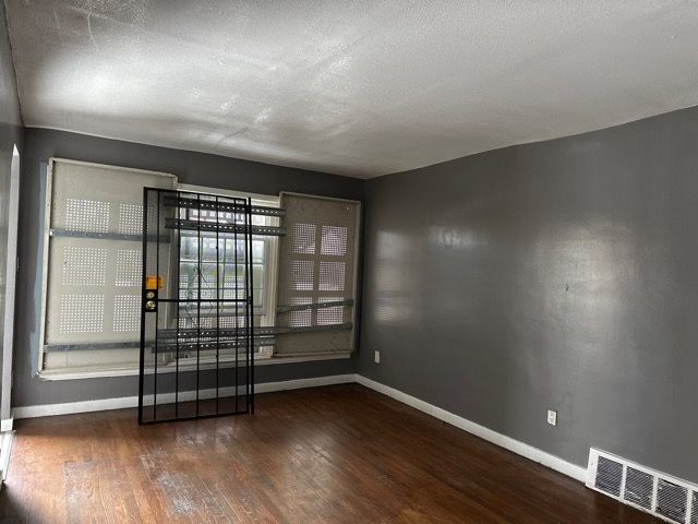 unfurnished room with dark hardwood / wood-style flooring and a textured ceiling