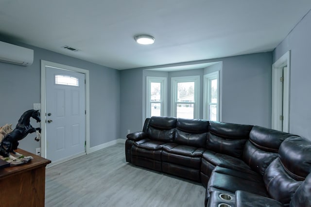 living room featuring a wealth of natural light, a wall mounted air conditioner, and light hardwood / wood-style flooring