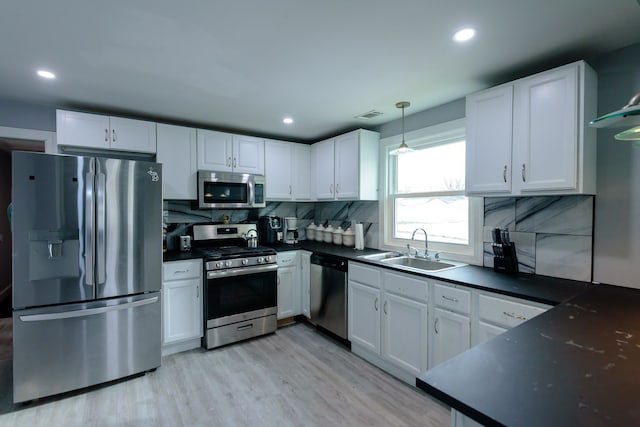 kitchen featuring sink, hanging light fixtures, appliances with stainless steel finishes, white cabinets, and backsplash