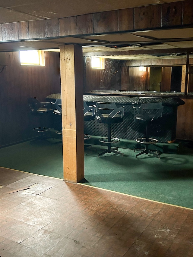 basement featuring indoor bar and wood walls