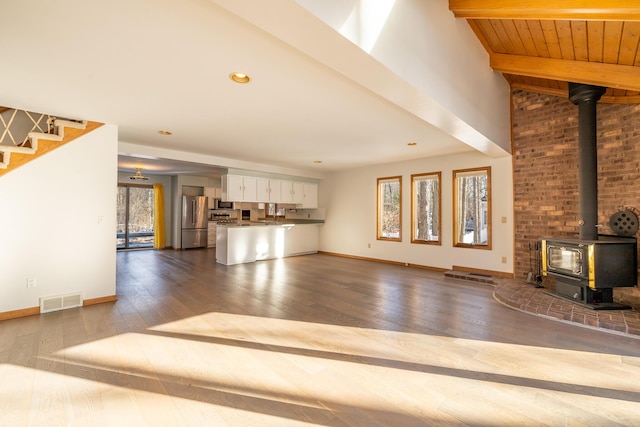 unfurnished living room with dark hardwood / wood-style flooring, vaulted ceiling with beams, wood ceiling, and a wood stove