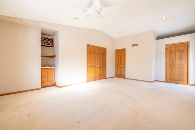 unfurnished bedroom with light carpet, indoor wet bar, lofted ceiling, and ceiling fan