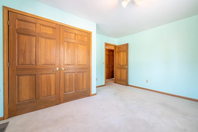 unfurnished bedroom with light colored carpet and a closet