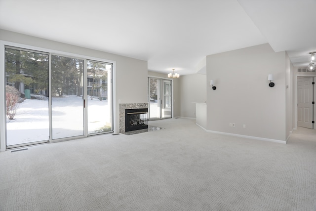 unfurnished living room with light colored carpet, a fireplace, and a chandelier