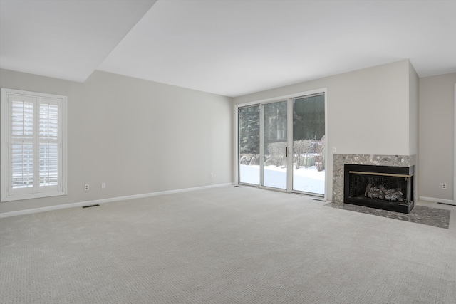 unfurnished living room with light colored carpet and a premium fireplace