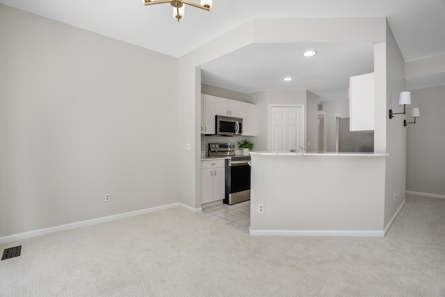 kitchen featuring light colored carpet, stainless steel appliances, kitchen peninsula, and white cabinets