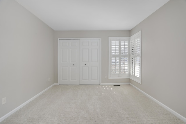 unfurnished bedroom featuring light colored carpet and a closet