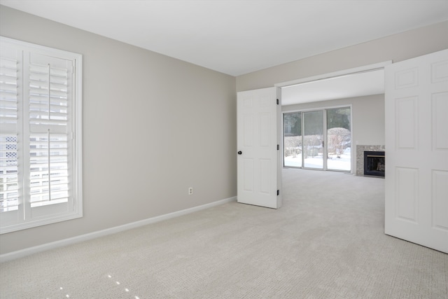 spare room featuring light colored carpet and a premium fireplace