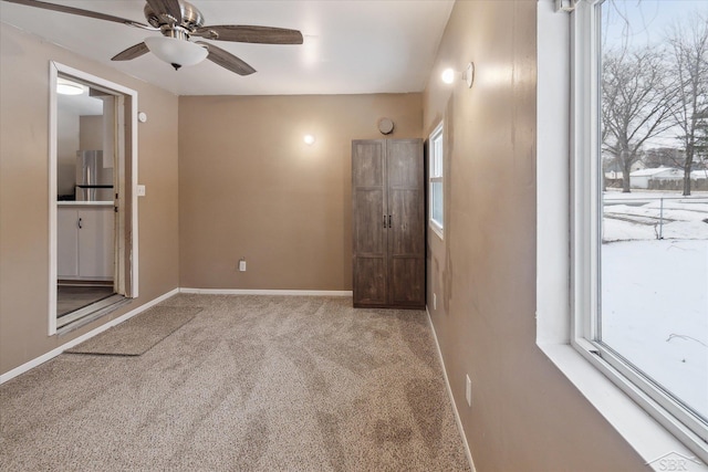 interior space featuring ceiling fan, light colored carpet, and stainless steel fridge