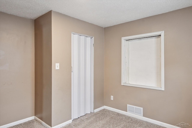 unfurnished room with carpet floors and a textured ceiling