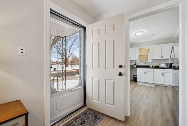 doorway to outside with sink and light wood-type flooring