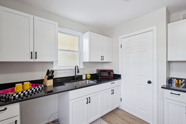 kitchen with sink, white cabinets, and light wood-type flooring