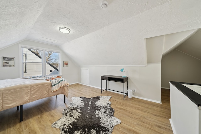 bedroom featuring hardwood / wood-style flooring, vaulted ceiling, and a textured ceiling