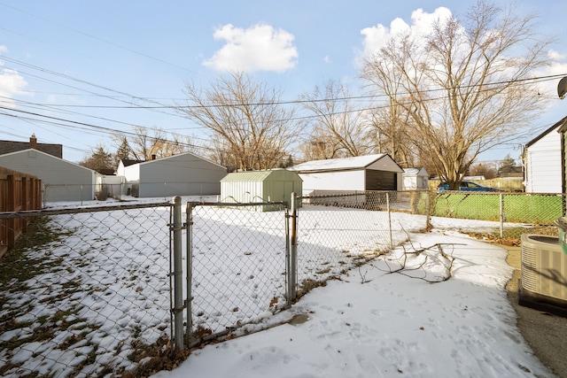 yard layered in snow with central air condition unit and a storage shed