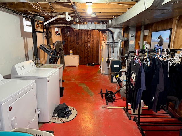 basement with gas water heater, washing machine and clothes dryer, and wooden walls