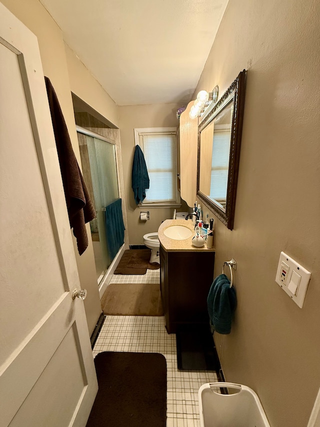 bathroom with vanity, toilet, and a shower with door