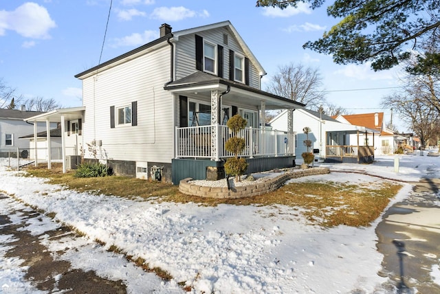 snow covered property featuring central AC and covered porch