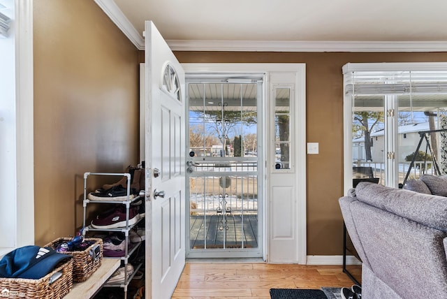 entryway with ornamental molding, a wealth of natural light, and light hardwood / wood-style flooring