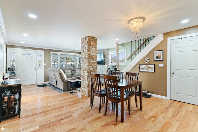 dining area with decorative columns, ornamental molding, a chandelier, and light hardwood / wood-style floors