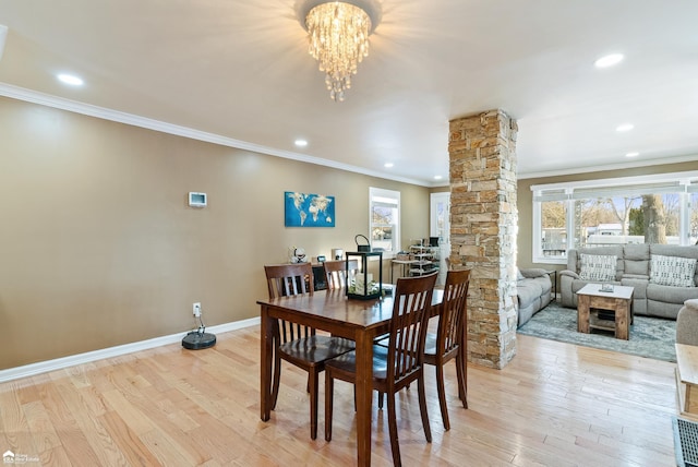 dining space with ornamental molding, a chandelier, decorative columns, and light wood-type flooring