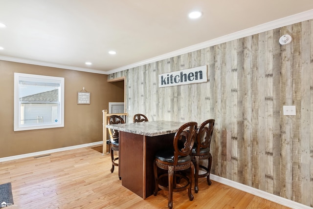 dining area featuring crown molding, light hardwood / wood-style floors, and wood walls