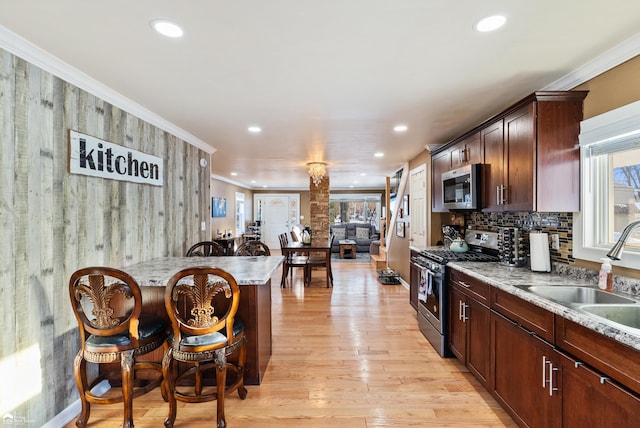 kitchen with light stone counters, stainless steel appliances, crown molding, and sink