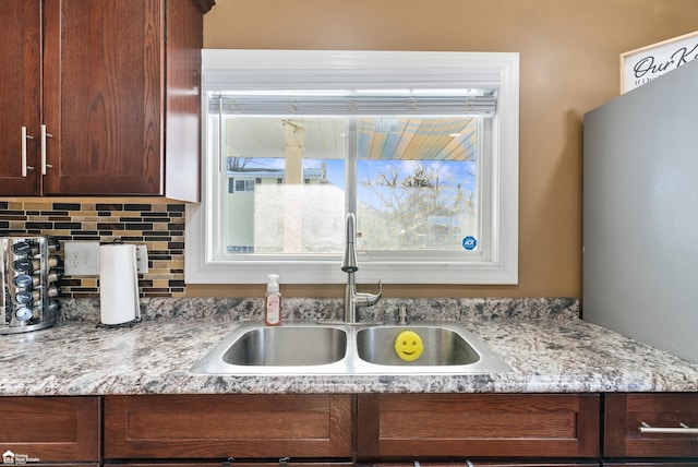 room details featuring tasteful backsplash, sink, and light stone counters