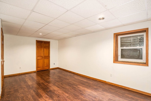 spare room with a paneled ceiling and dark hardwood / wood-style floors