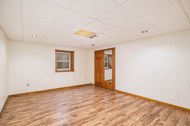 spare room featuring a drop ceiling and light wood-type flooring