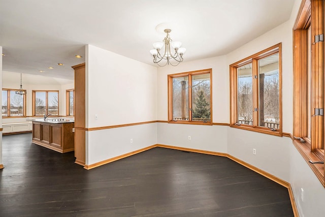 empty room with a notable chandelier, dark wood-type flooring, and plenty of natural light