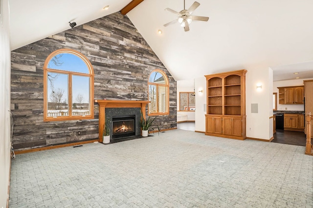 unfurnished living room featuring beamed ceiling, ceiling fan, carpet flooring, and high vaulted ceiling