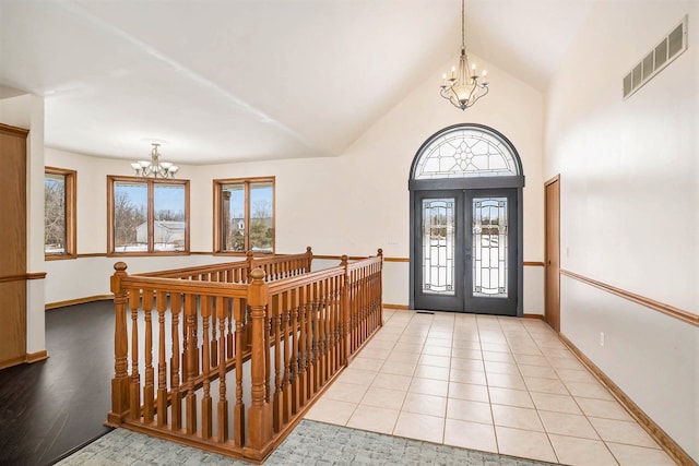 foyer featuring an inviting chandelier, a healthy amount of sunlight, french doors, and light tile patterned floors