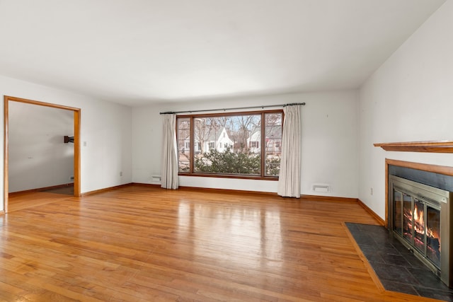 unfurnished living room with a tile fireplace and light hardwood / wood-style flooring