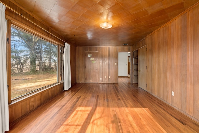 unfurnished room with plenty of natural light, light hardwood / wood-style floors, and wood walls