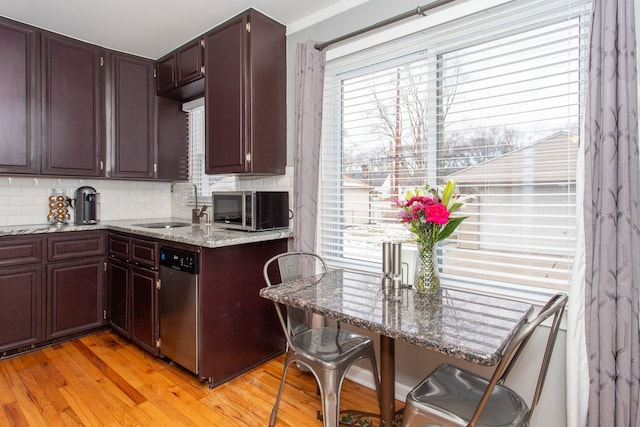 kitchen with sink, stainless steel appliances, stone countertops, decorative backsplash, and light wood-type flooring