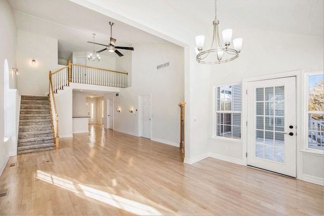 unfurnished living room with ceiling fan with notable chandelier, high vaulted ceiling, and light hardwood / wood-style flooring