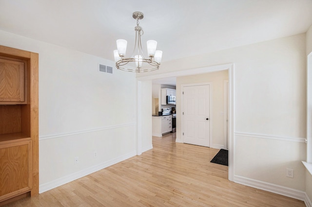 unfurnished dining area with a notable chandelier and light hardwood / wood-style flooring