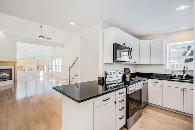 kitchen featuring sink, white cabinetry, appliances with stainless steel finishes, dark stone counters, and light hardwood / wood-style floors