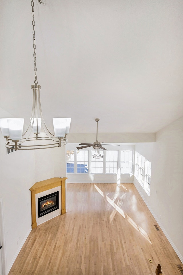 unfurnished living room with wood-type flooring and ceiling fan with notable chandelier