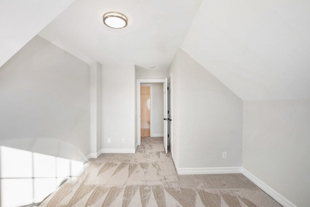 additional living space featuring vaulted ceiling and light carpet